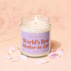 Glass jar candle with lit wick, purple label reads "World's Best Mother-in-Law".