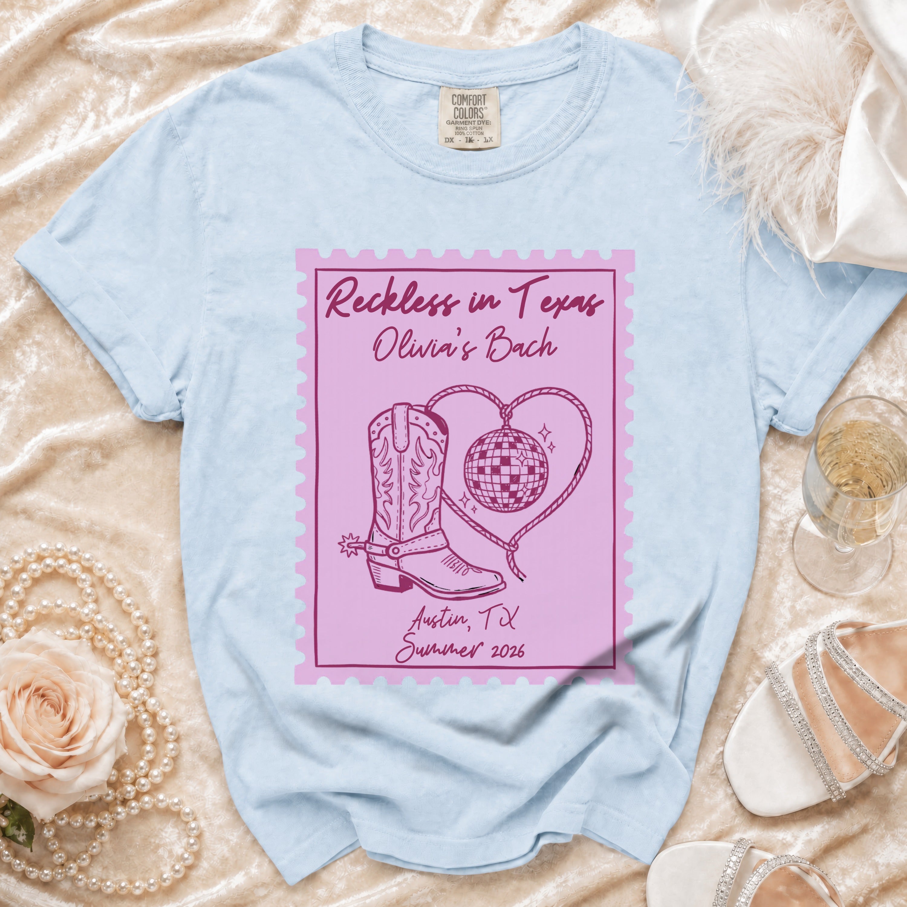 Light blue t-shirt with "Reckless in Texas Olivia's Bach Austin, TX Summer 2026" graphic.