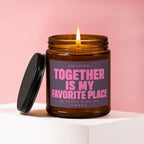 Amber glass candle with lit wick and pink text reading "Together is my favorite place."