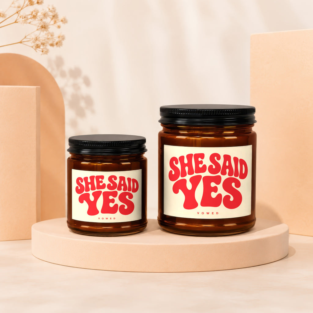 Two amber glass jars with black lids, labels read "SHE SAID YES".