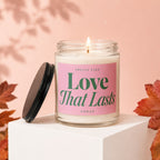 Scented candle labeled "Love That Lasts" with a lit wick and open lid nearby.