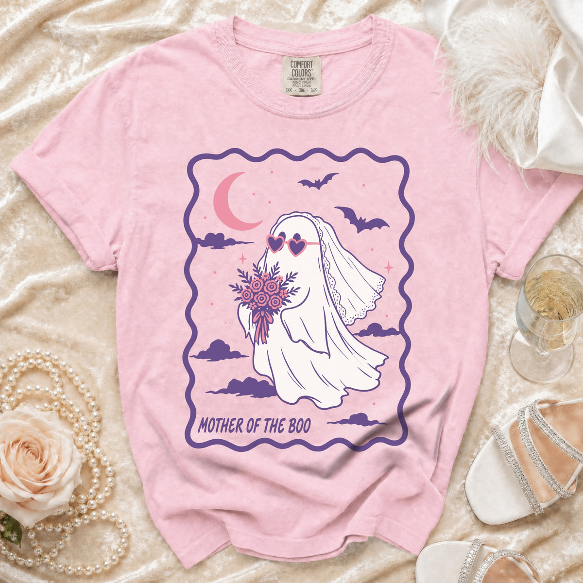 Pink t-shirt with a ghost graphic wearing heart sunglasses holding flowers, text "MOTHER OF THE BOO".