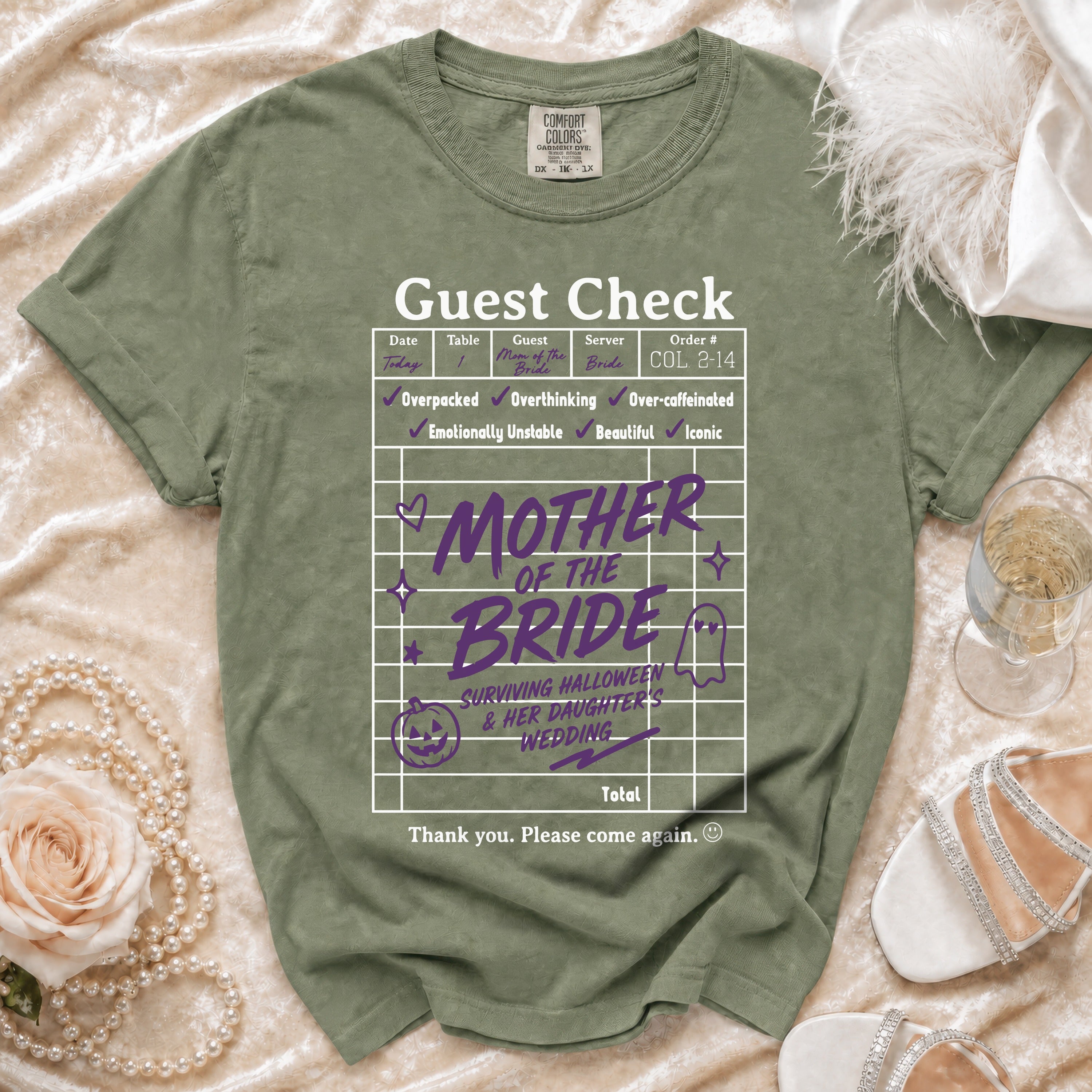 Green t-shirt with "Guest Check Mother of the Bride Surviving Halloween & Her Daughter's Wedding" graphic.