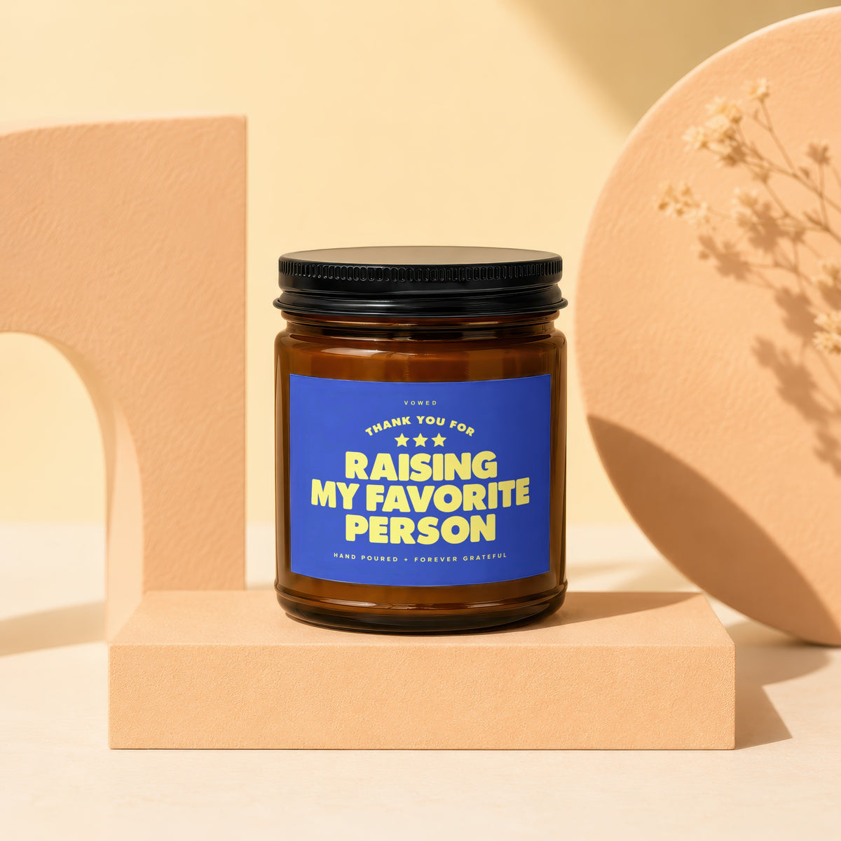 Amber glass candle with blue label reading "Raising My Favorite Person".