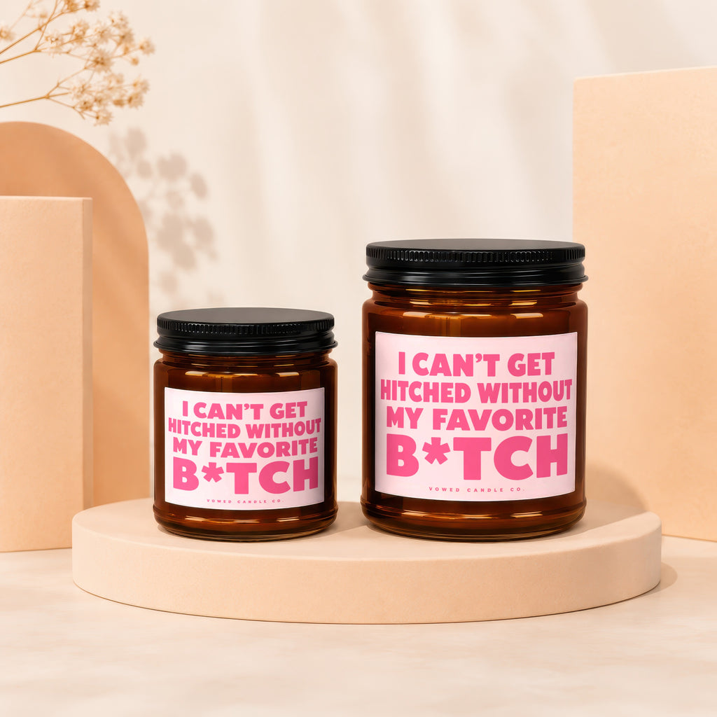 Two amber glass candles with pink labels reading "I can't get hitched without my favorite B*tch."