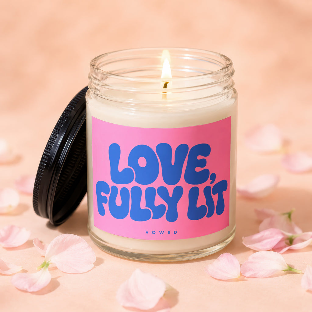 Candle with a lit wick and a pink label reading "LOVE, FULLY LIT".