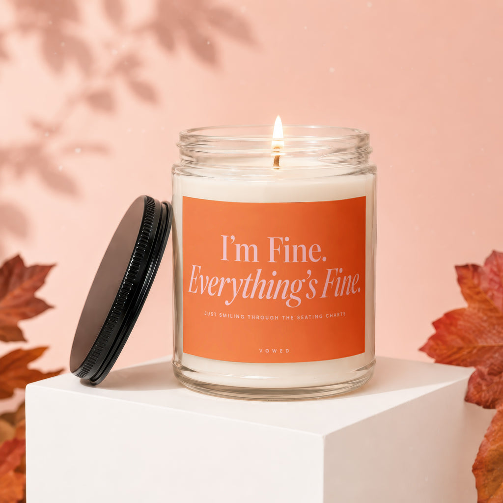 Lit candle in glass jar with orange label reading "I'm Fine. Everything's Fine."