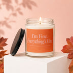 Lit candle in glass jar with orange label reading "I'm Fine. Everything's Fine."