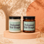 Two candles with "Professional Bride Wrangler" labels sit on a peach pedestal.