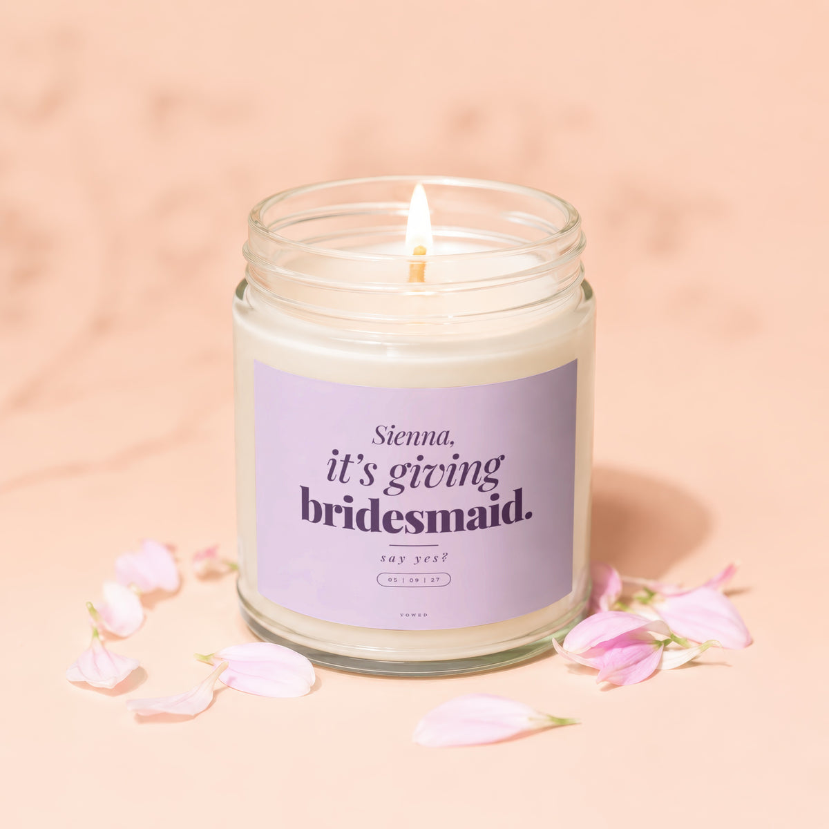 Candle with purple label saying "Sienna, it's giving bridesmaid. say yes?"