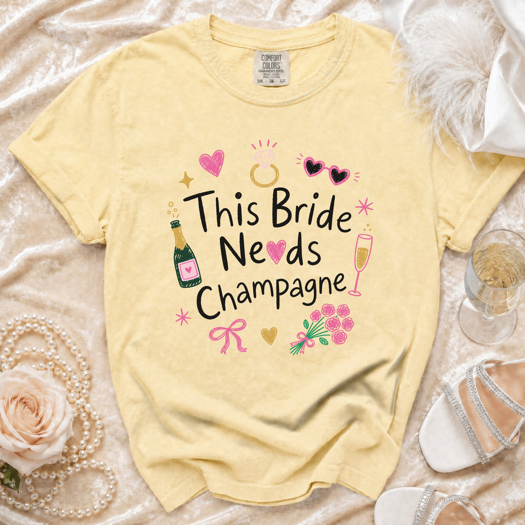 Yellow t-shirt with "This Bride Needs Champagne" graphic and bridal accessories.