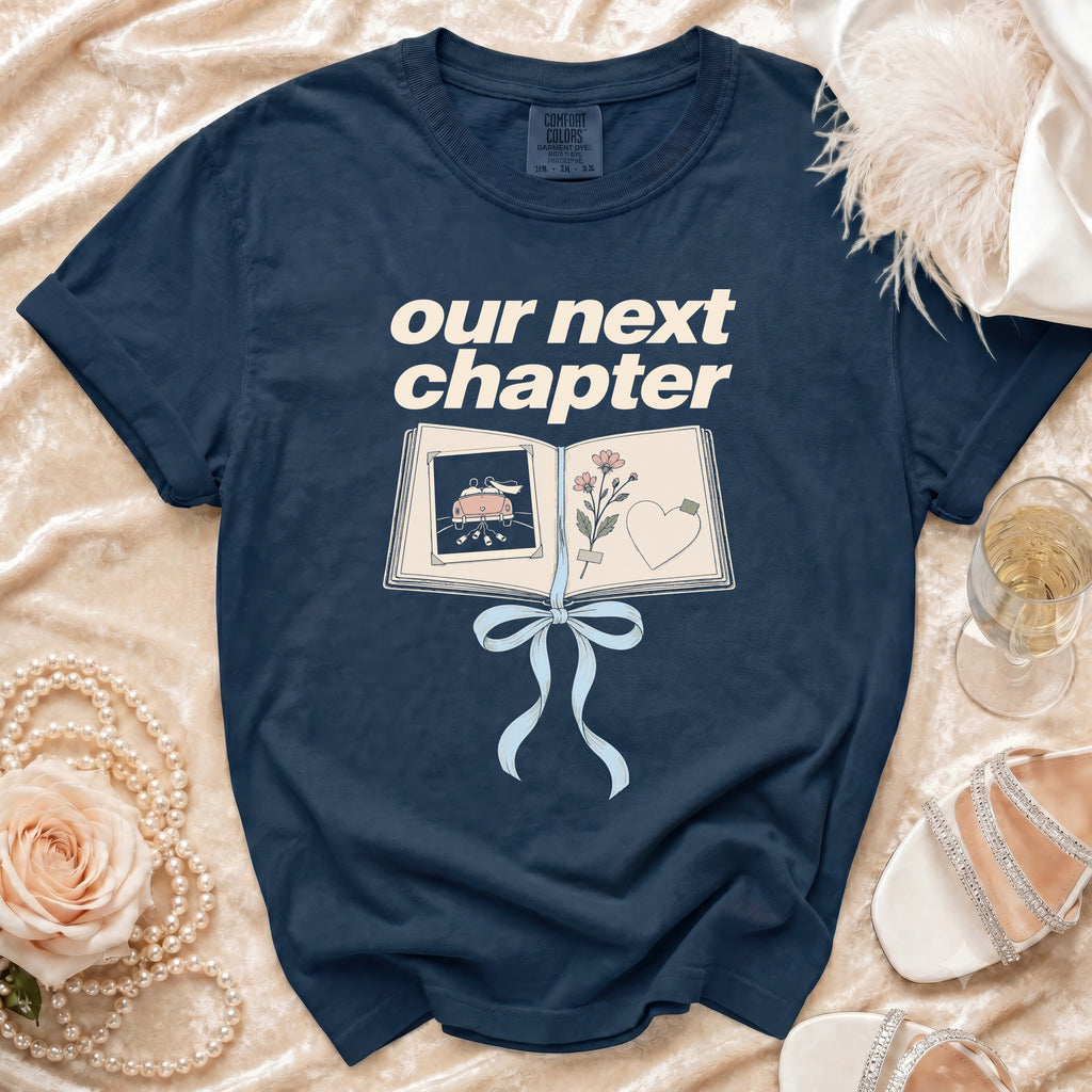Navy t-shirt with "our next chapter" text over an open book graphic.