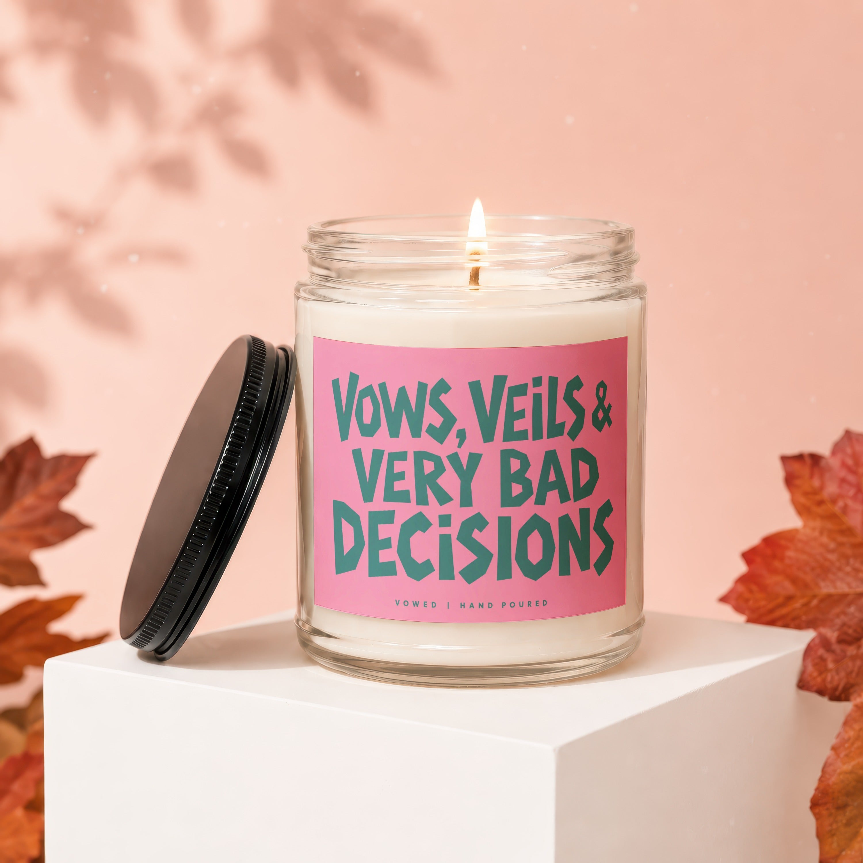 Scented candle with text "Vows, Veils & Very Bad Decisions" on a pink label.