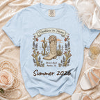 Light blue t-shirt with cowboy boot, cactus, and text "Reckless in Texas, Olivia's Bach Summer 2026".