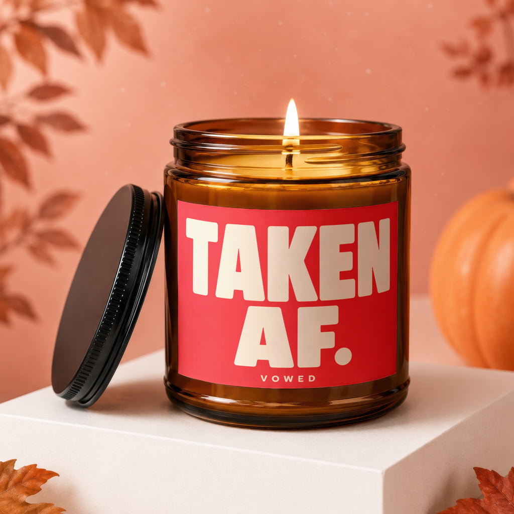 Amber jar candle with red label reading "TAKEN AF. VOWED."