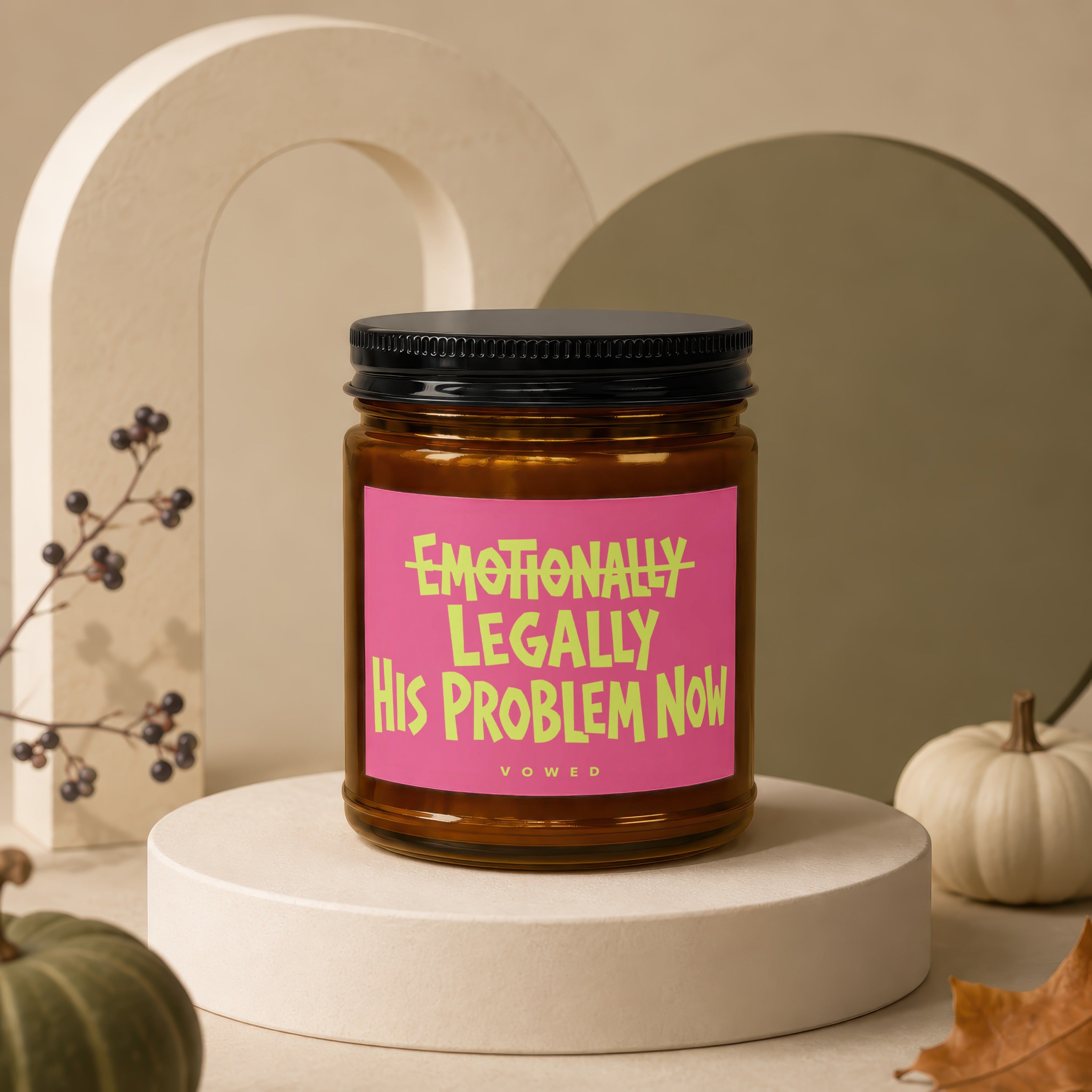 Amber jar candle with pink label reading "Emotionally Legally His Problem Now"