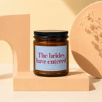Amber candle with light blue label reading "The brides have entered", VOWED.