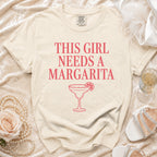 Cream t-shirt with "This Girl Needs A Margarita" text and margarita graphic.