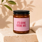 Amber jar candle with pink label reading "It's Giving Future Mrs."