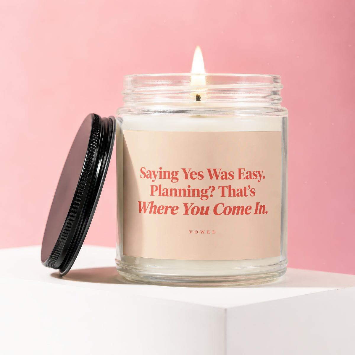 Candle with a lit wick and label reading "Saying Yes Was Easy. Planning? That's Where You Come In."