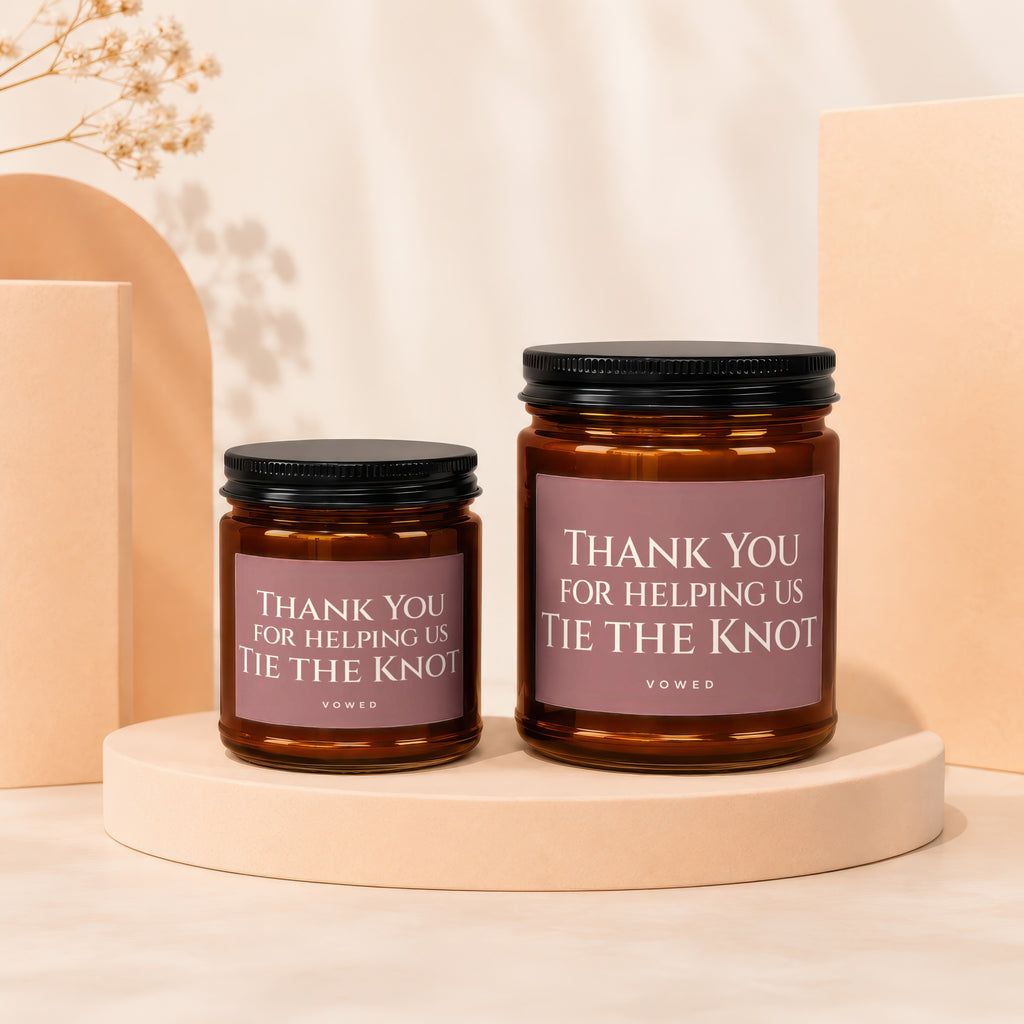 Two amber glass candles with black lids, featuring "Thank You For Helping Us Tie The Knot" text.