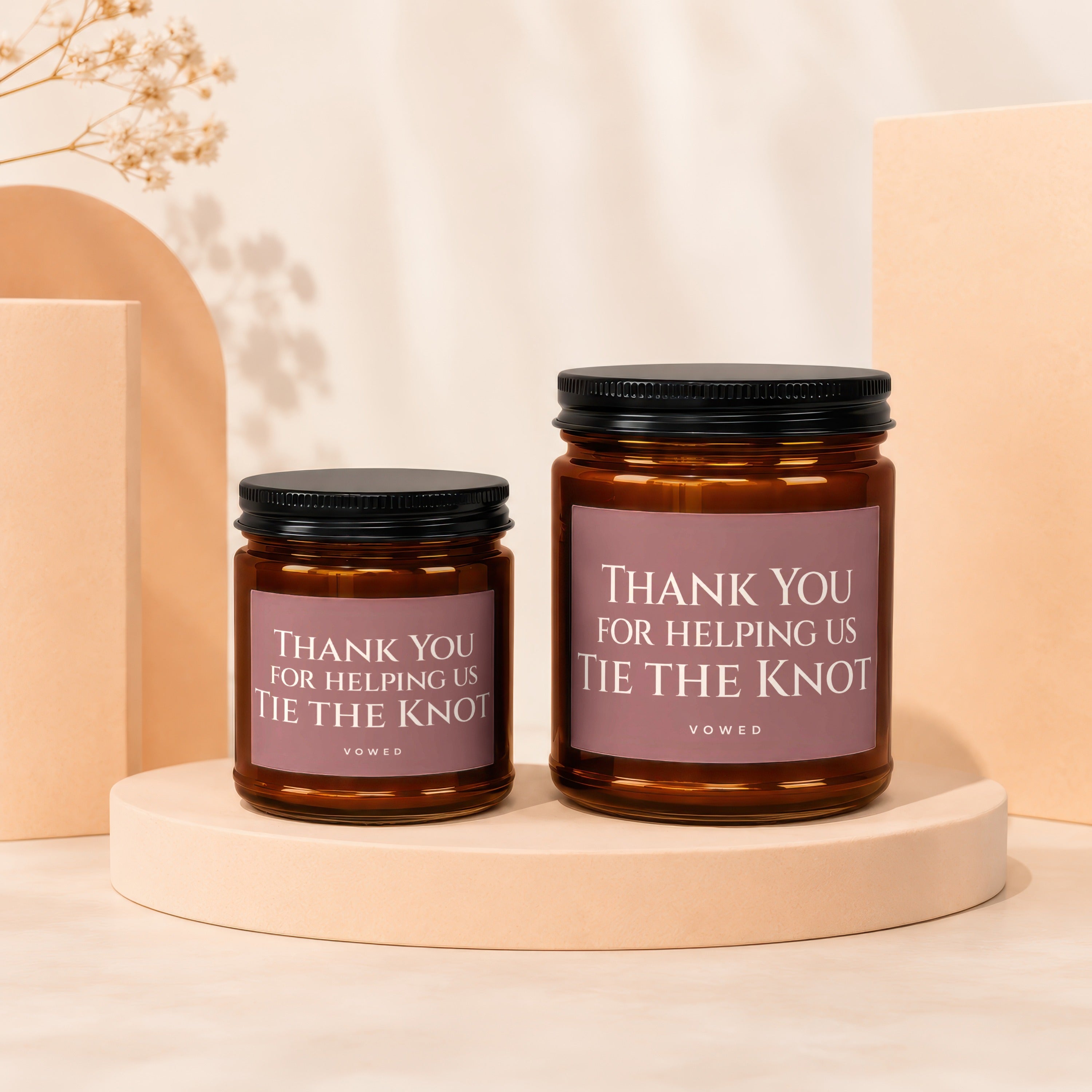 Two amber glass candles with black lids, featuring "Thank You For Helping Us Tie The Knot" text.