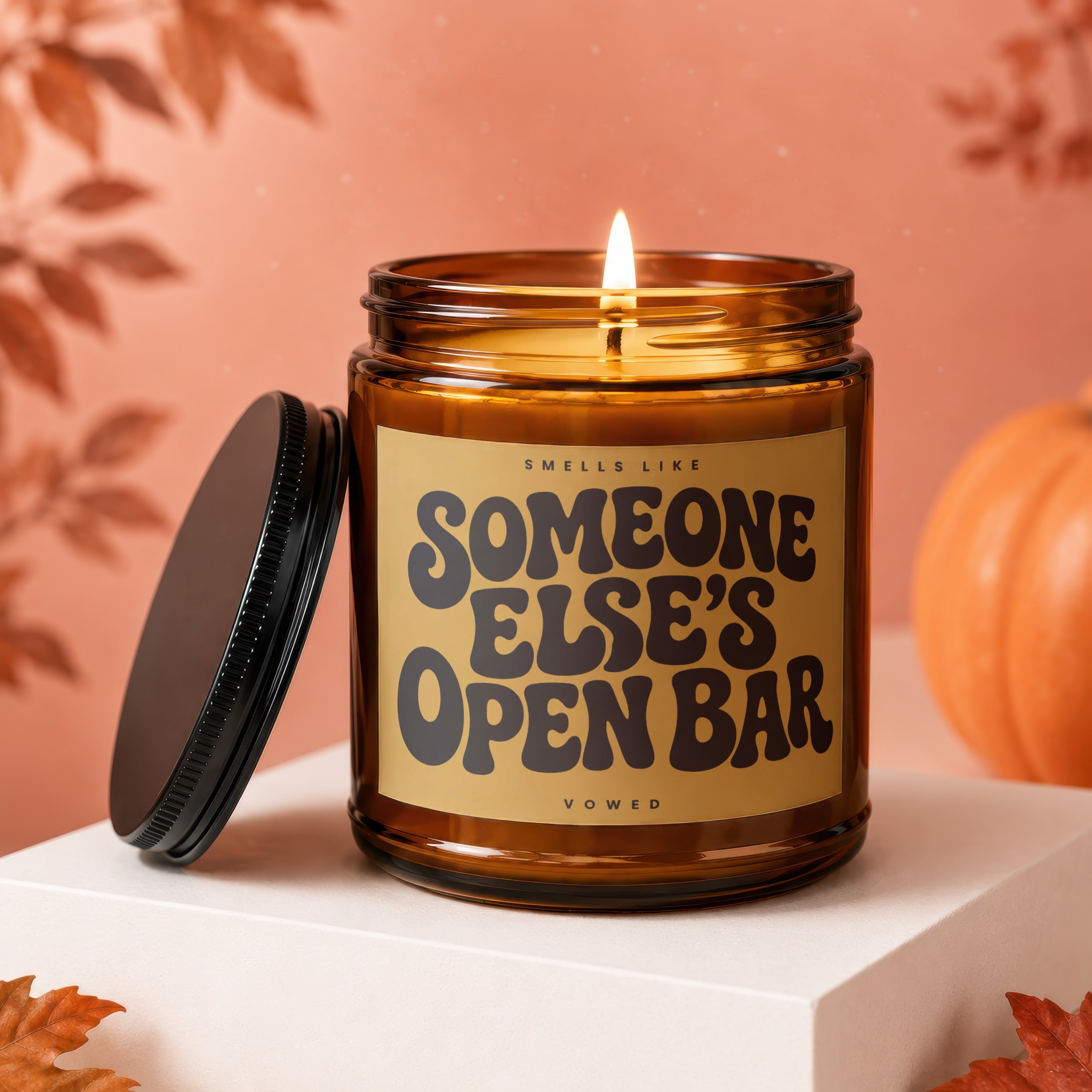 Amber glass candle with lit flame and "Smells Like Someone Else's Open Bar" label.