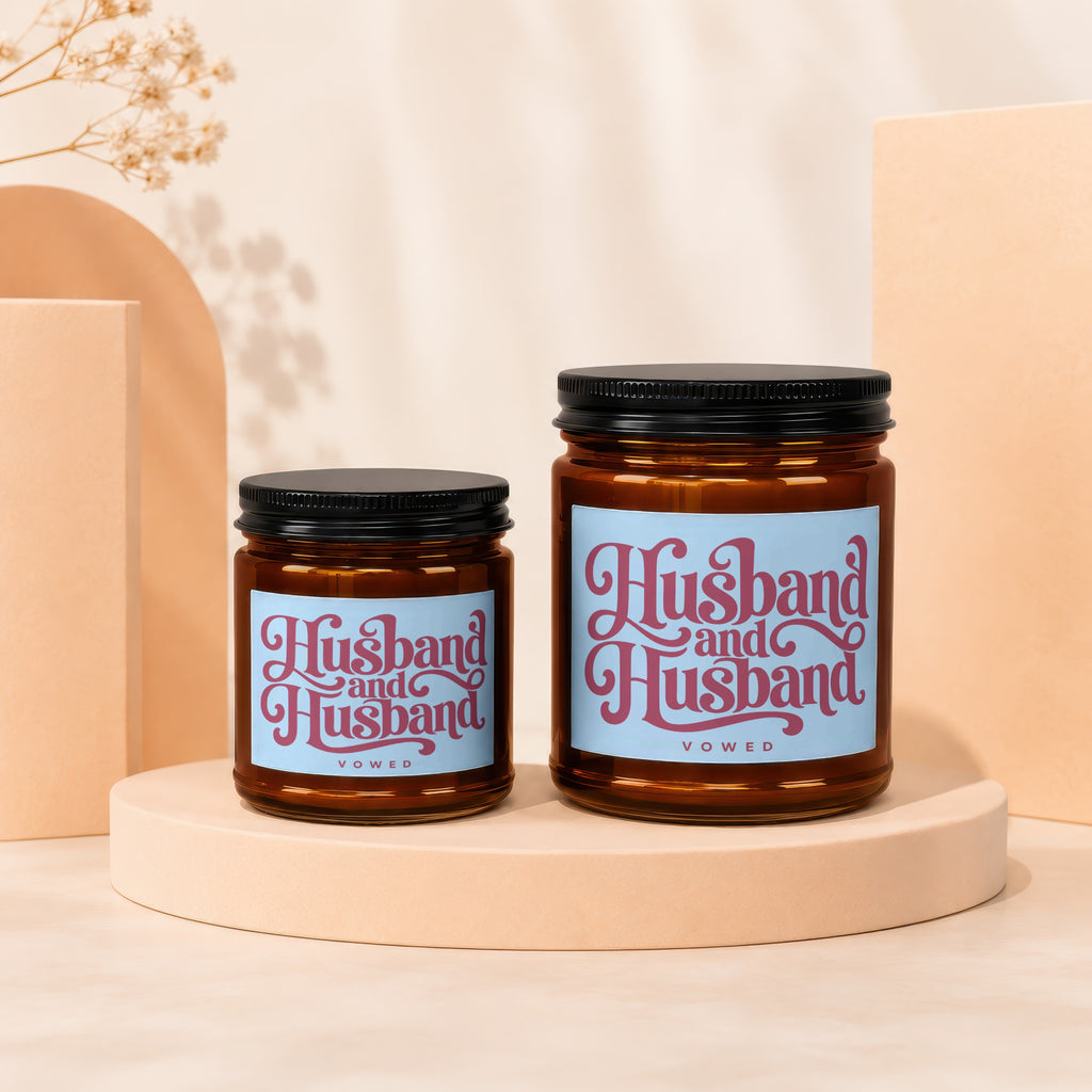 Two amber glass candles with "Husband and Husband VOWED" text on blue labels.