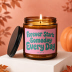 Amber jar candle with pink label that reads "Forever Starts Someday Every Day"