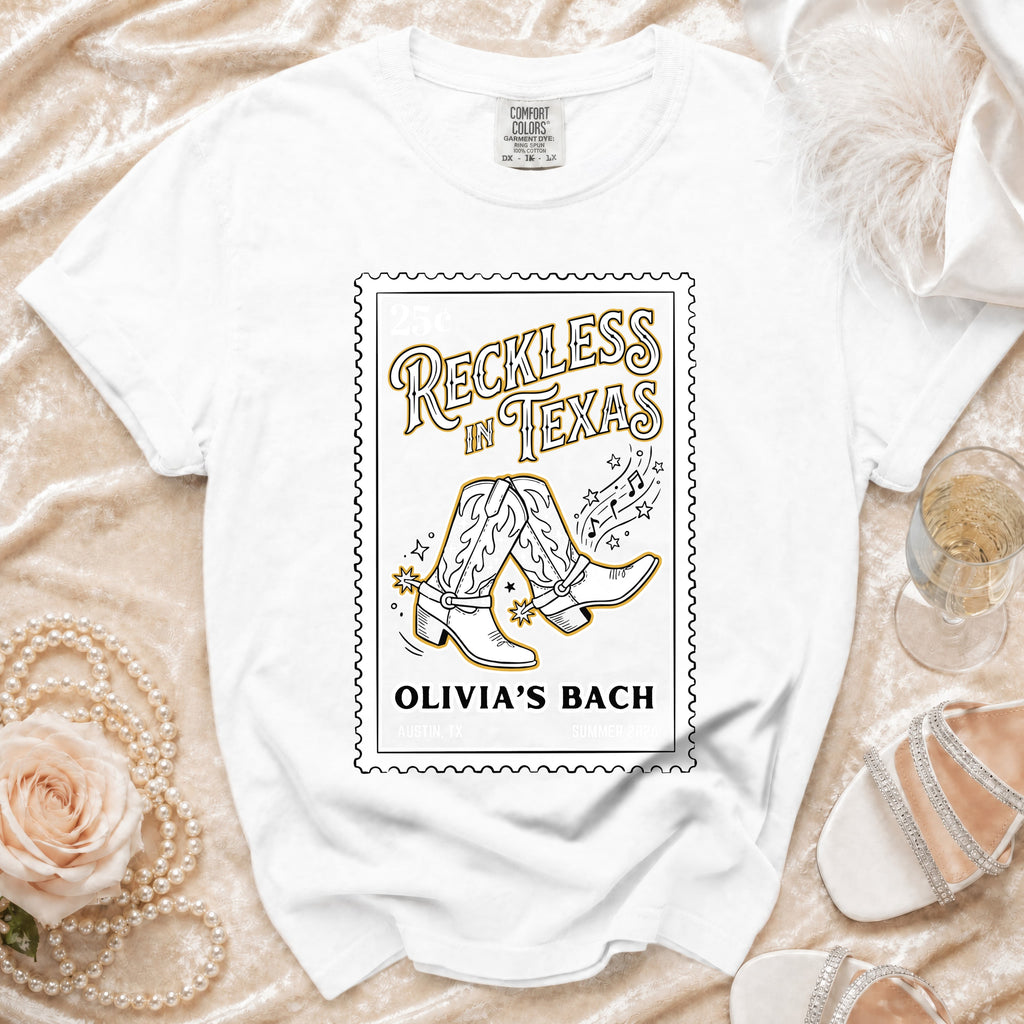 White t-shirt with "Reckless in Texas" and cowboy boots graphic.