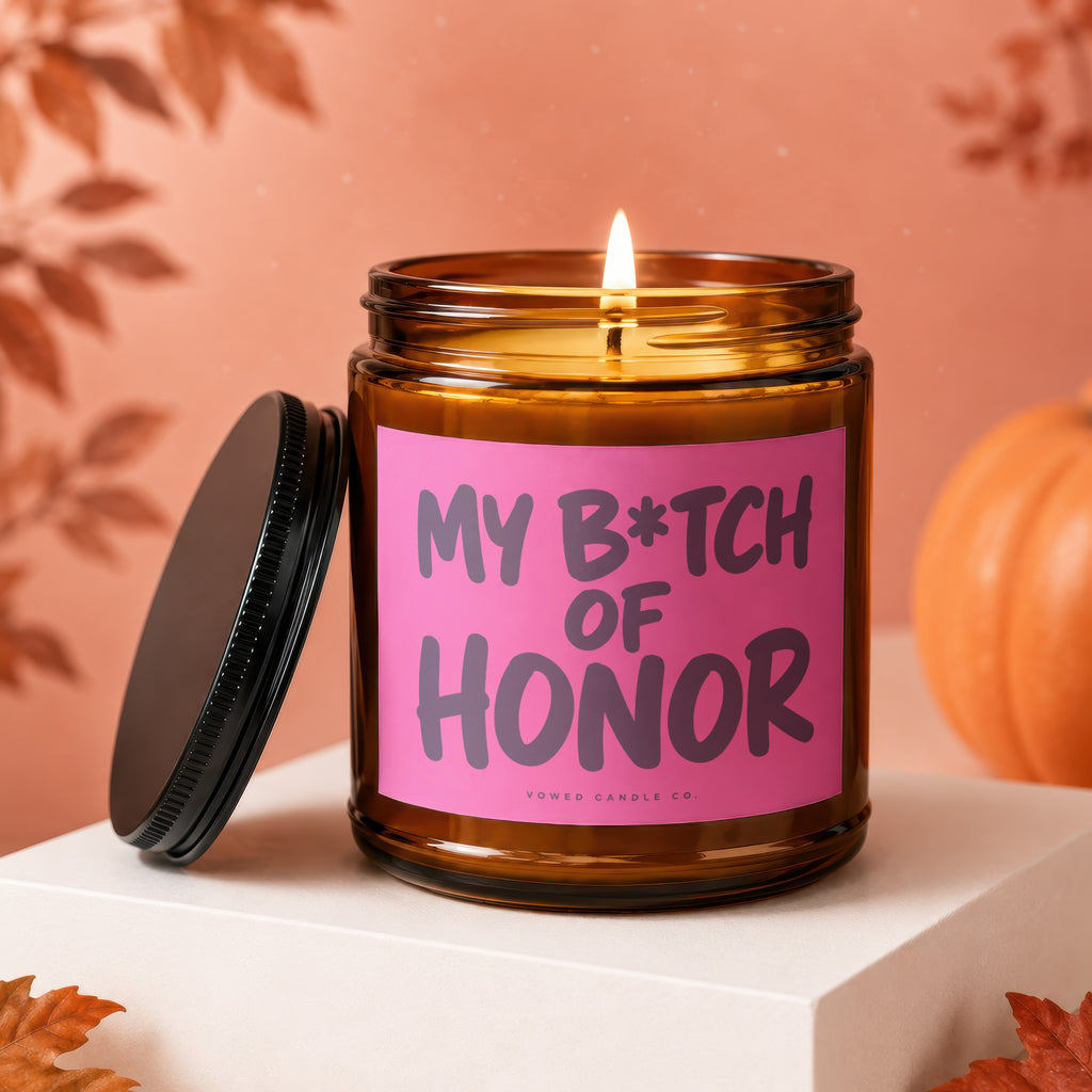 Candle with "My B*tch of Honor" text on pink label, lid off.