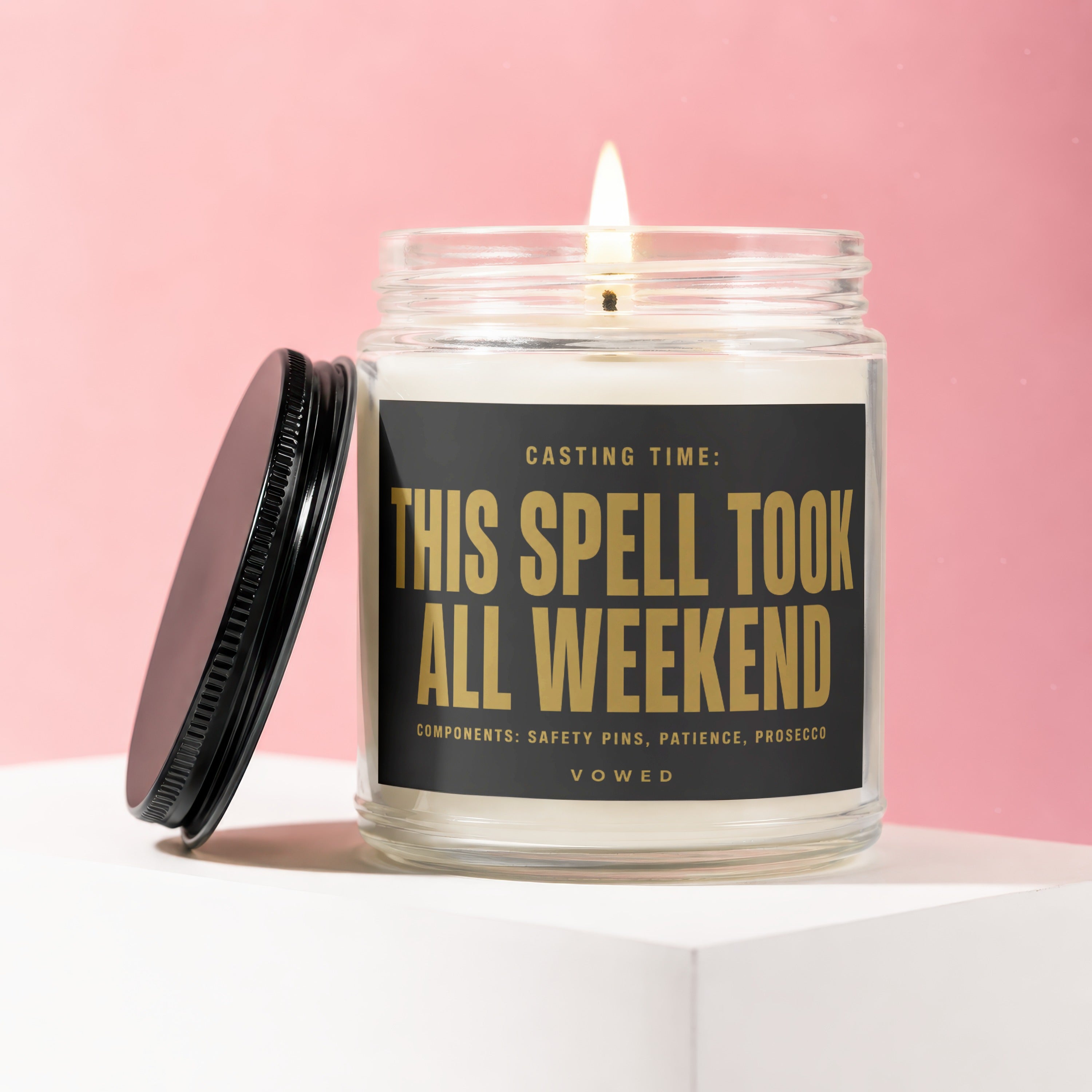 Glass candle with flame, black lid askew. Label reads: "THIS SPELL TOOK ALL WEEKEND".