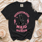 Black t-shirt with pink "Overestimated Maid of Honor" text and champagne glass graphic.