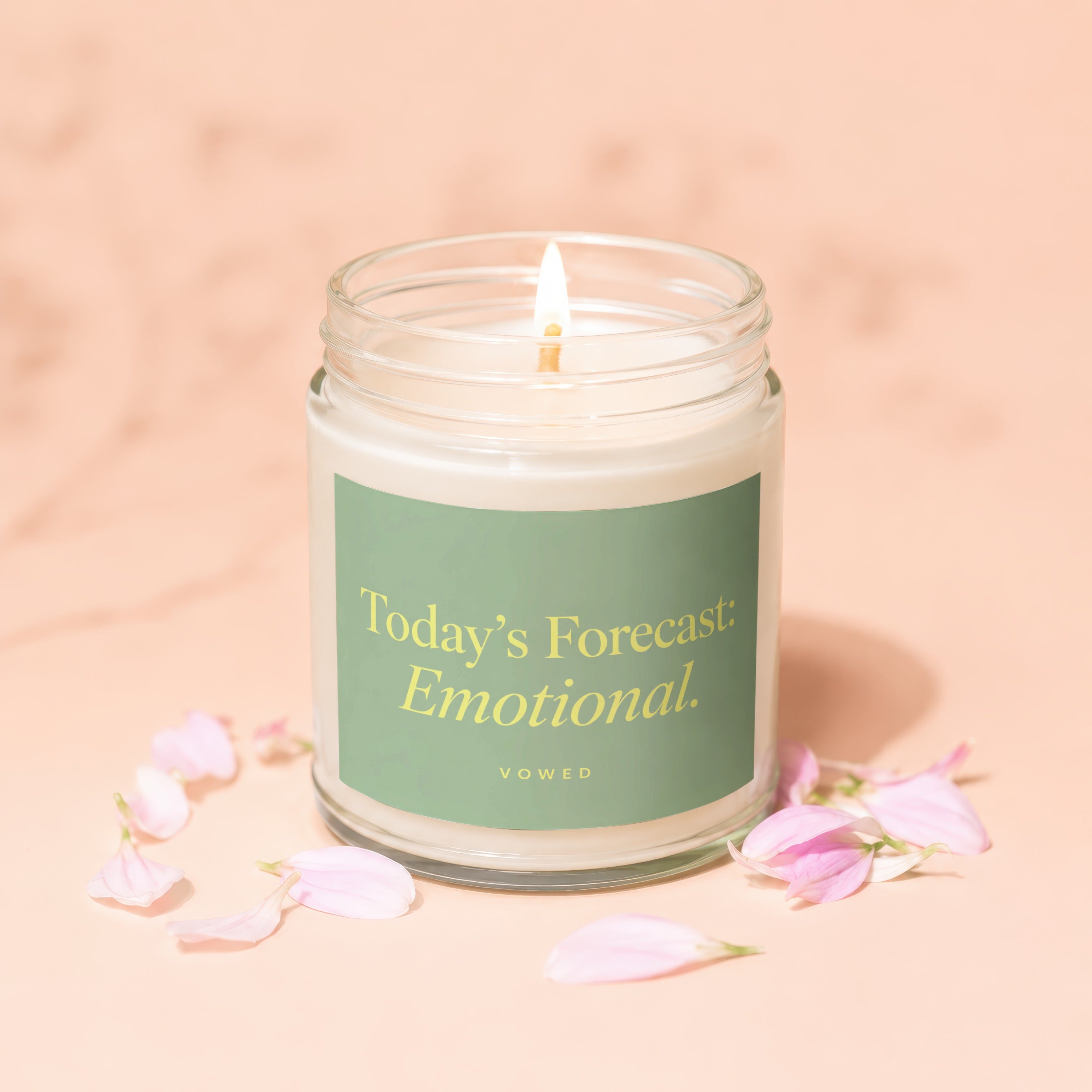 Lit candle in glass jar with green label reading "Today's Forecast: Emotional."