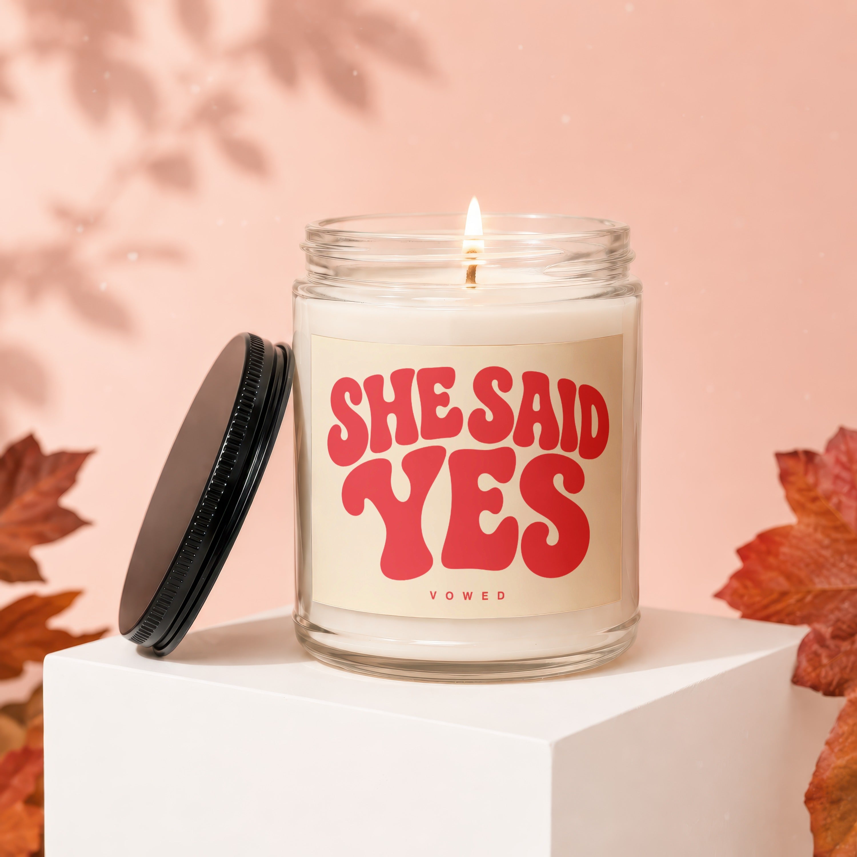 Candle with "SHE SAID YES" text on a retro-style label, lit flame.