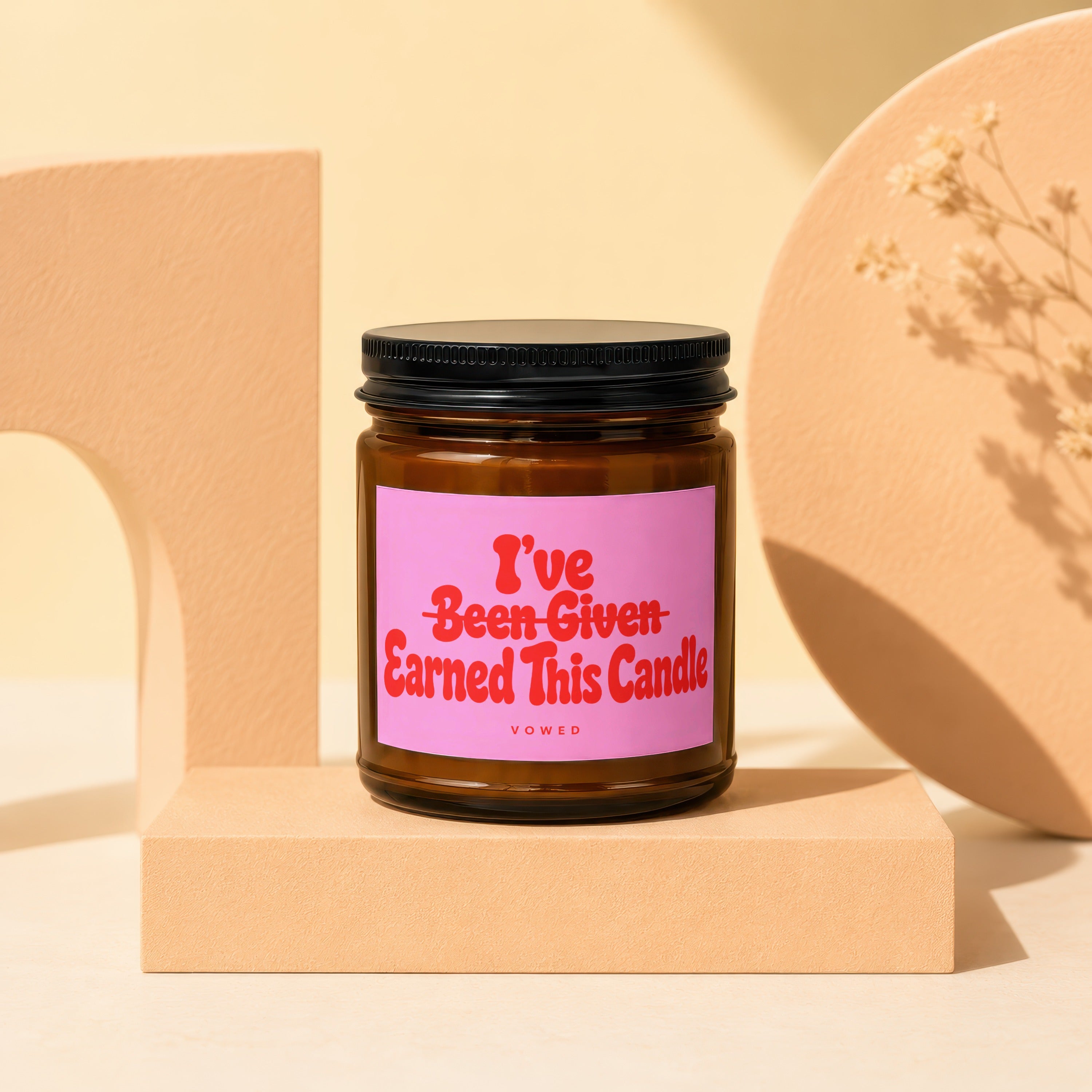 Brown glass candle with pink label reading "I've Been Given Earned This Candle".