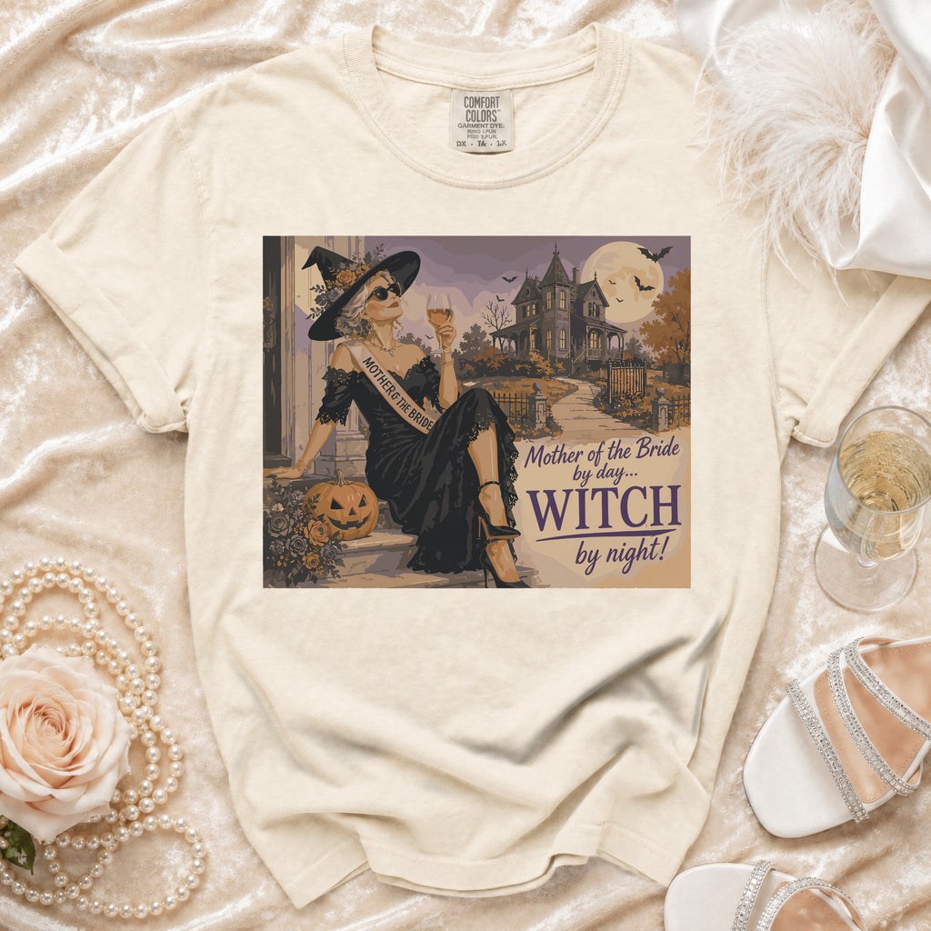 Cream t-shirt with graphic of a witch sash, "Mother of the Bride by day... Witch by night!" text.