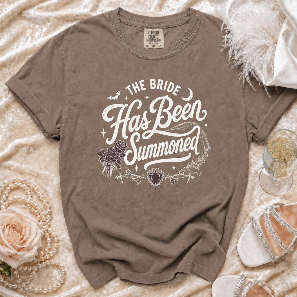 Brown t-shirt with "The Bride Has Been Summoned" text and gothic graphics.