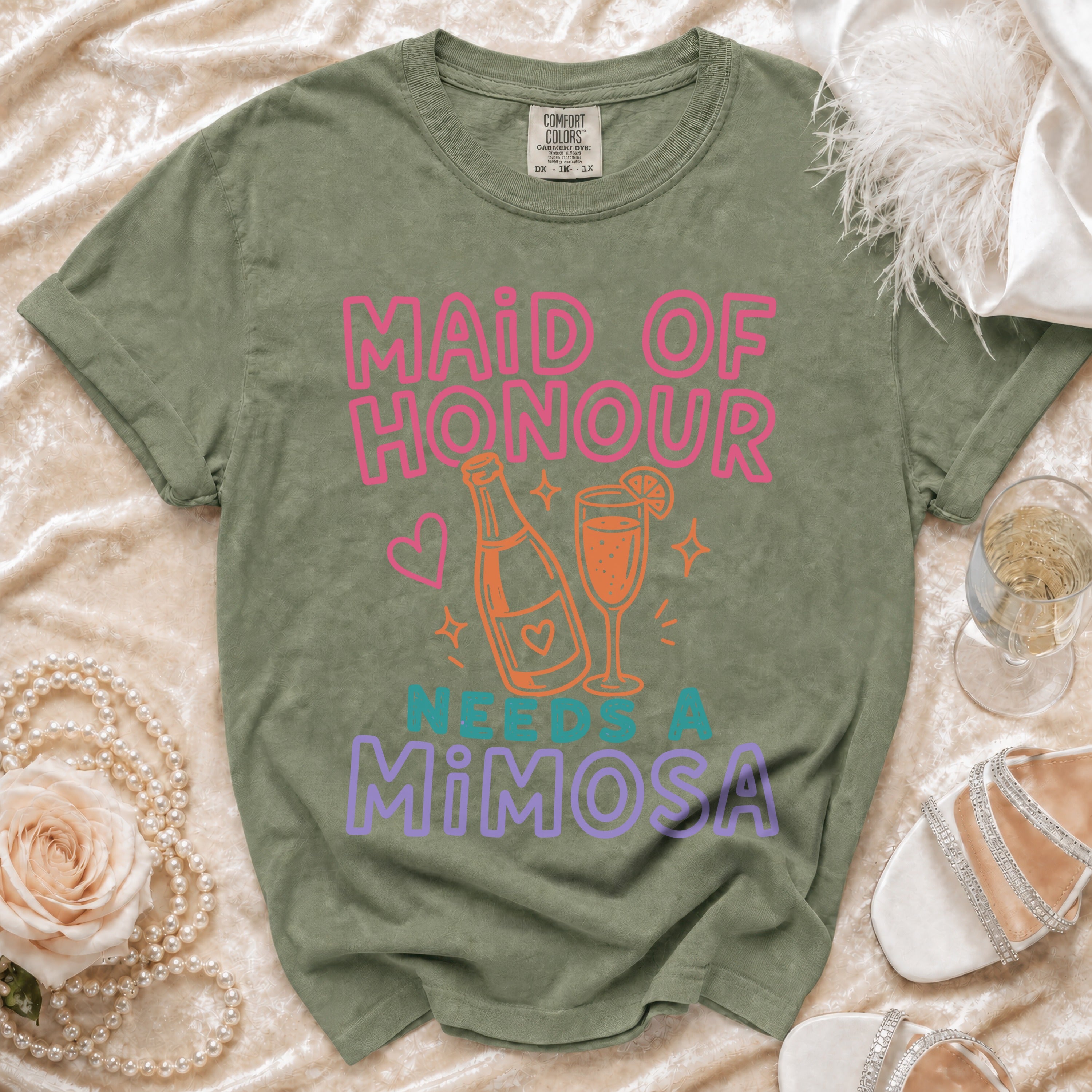 Olive green t-shirt with "Maid of Honour Needs a Mimosa" text and drink graphic.