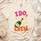 Cream t-shirt with "I DO CREW" text, champagne bottle, and stars design.
