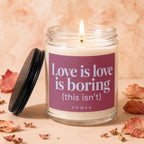 Lit glass jar candle with "Love is love is boring (this isn't) VOWED" text.