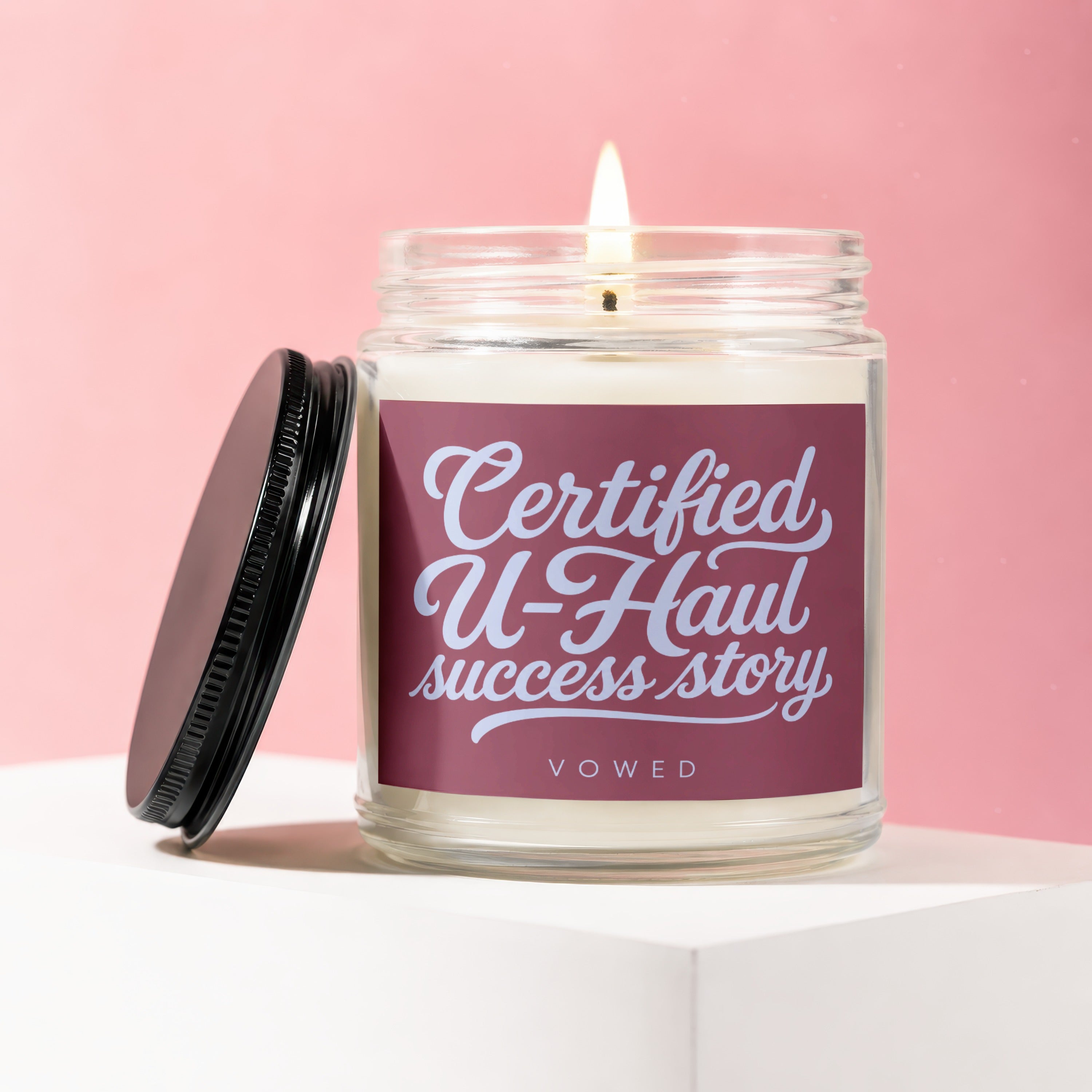 Candle with burgundy label reading "Certified U-Haul success story" VOWED.