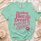Aqua t-shirt with pink text "Holding Her Dress and Her Secrets."