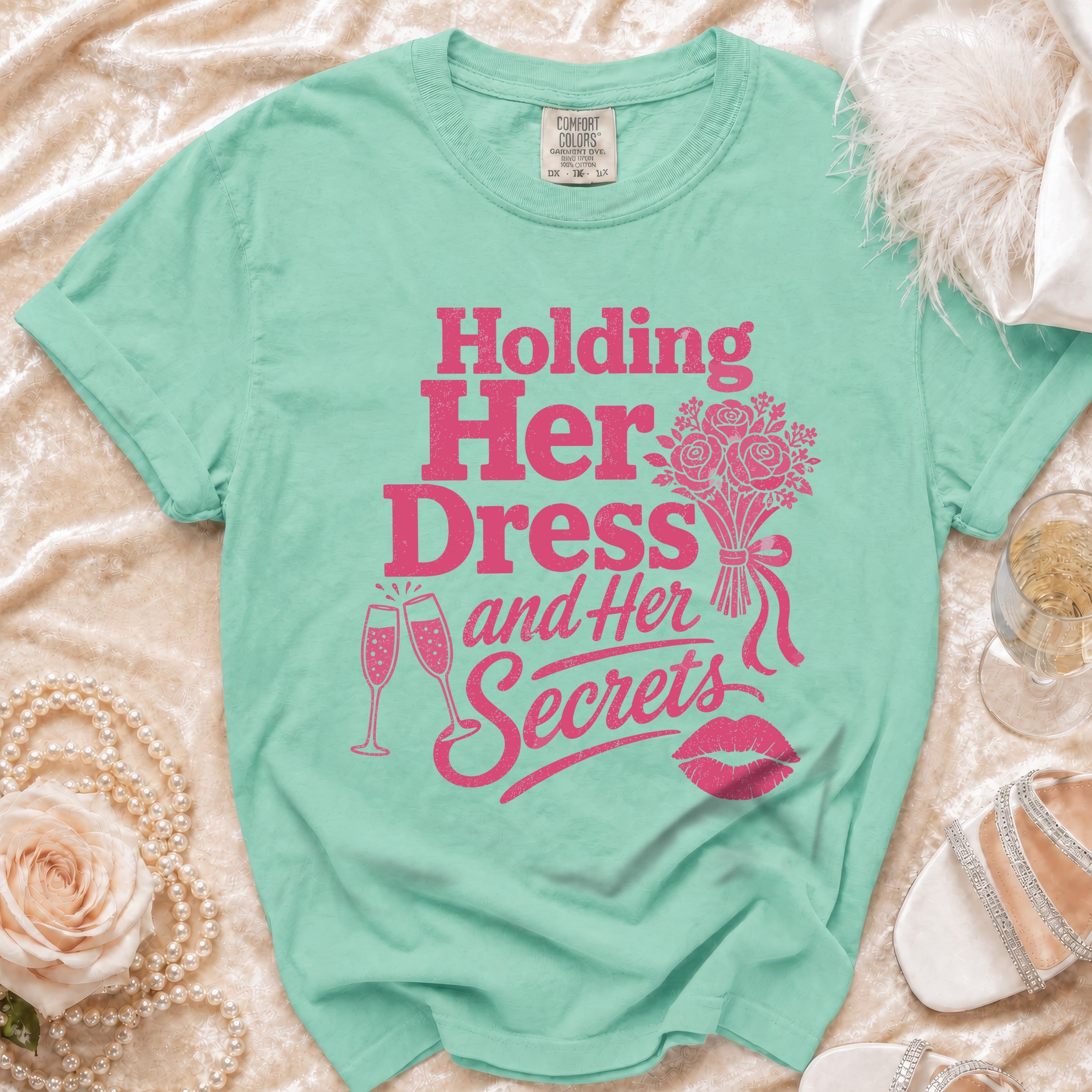 Aqua t-shirt with pink text "Holding Her Dress and Her Secrets."
