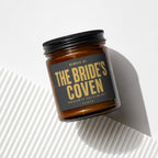 Amber candle with black lid, label reads "THE BRIDE'S COVEN".