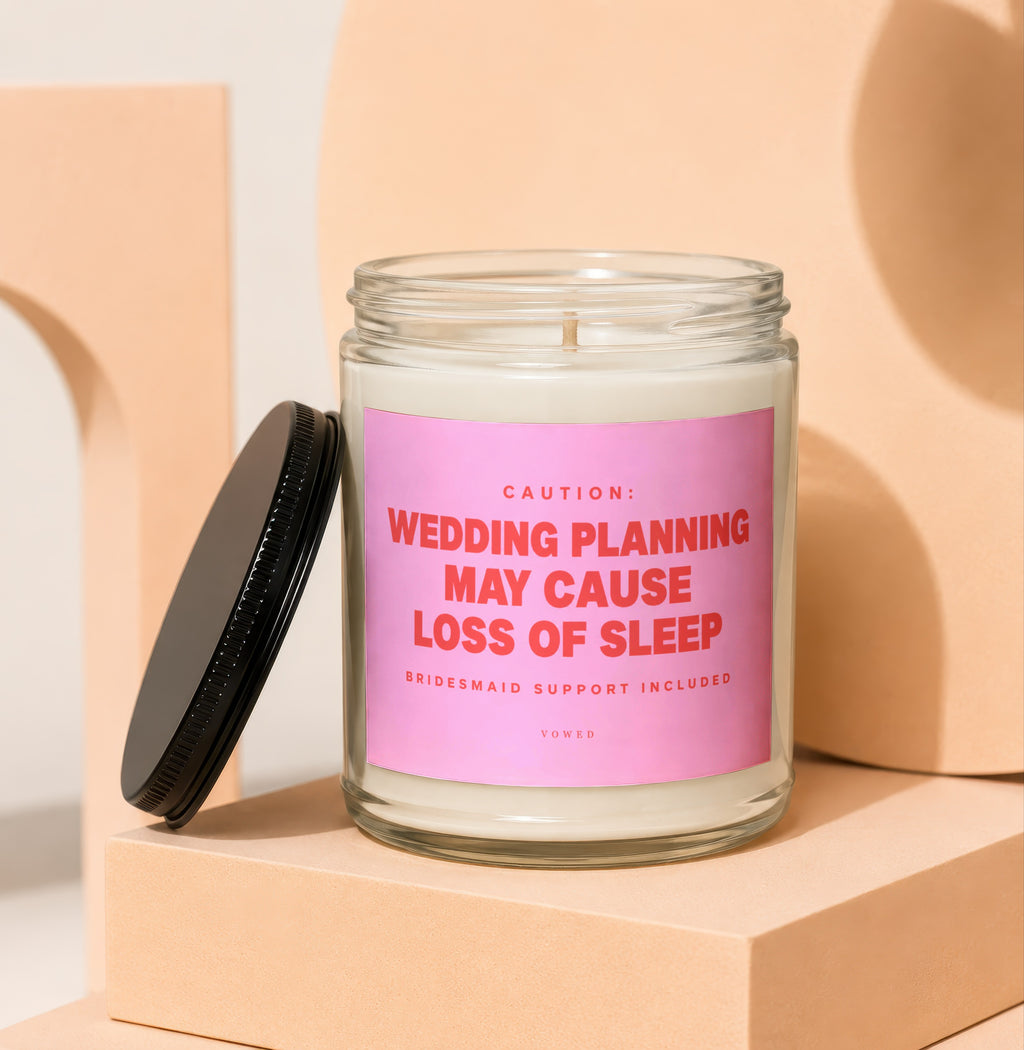 Glass candle with pink label that reads "Wedding planning may cause loss of sleep."