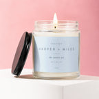 Glass candle with lit wick, featuring label "Engaged Harper + Miles the easiest yes 06 | 14 | 27"