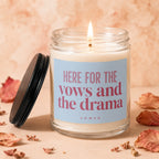 Lit candle in a glass jar with a blue label reading "HERE FOR THE vows and the drama"