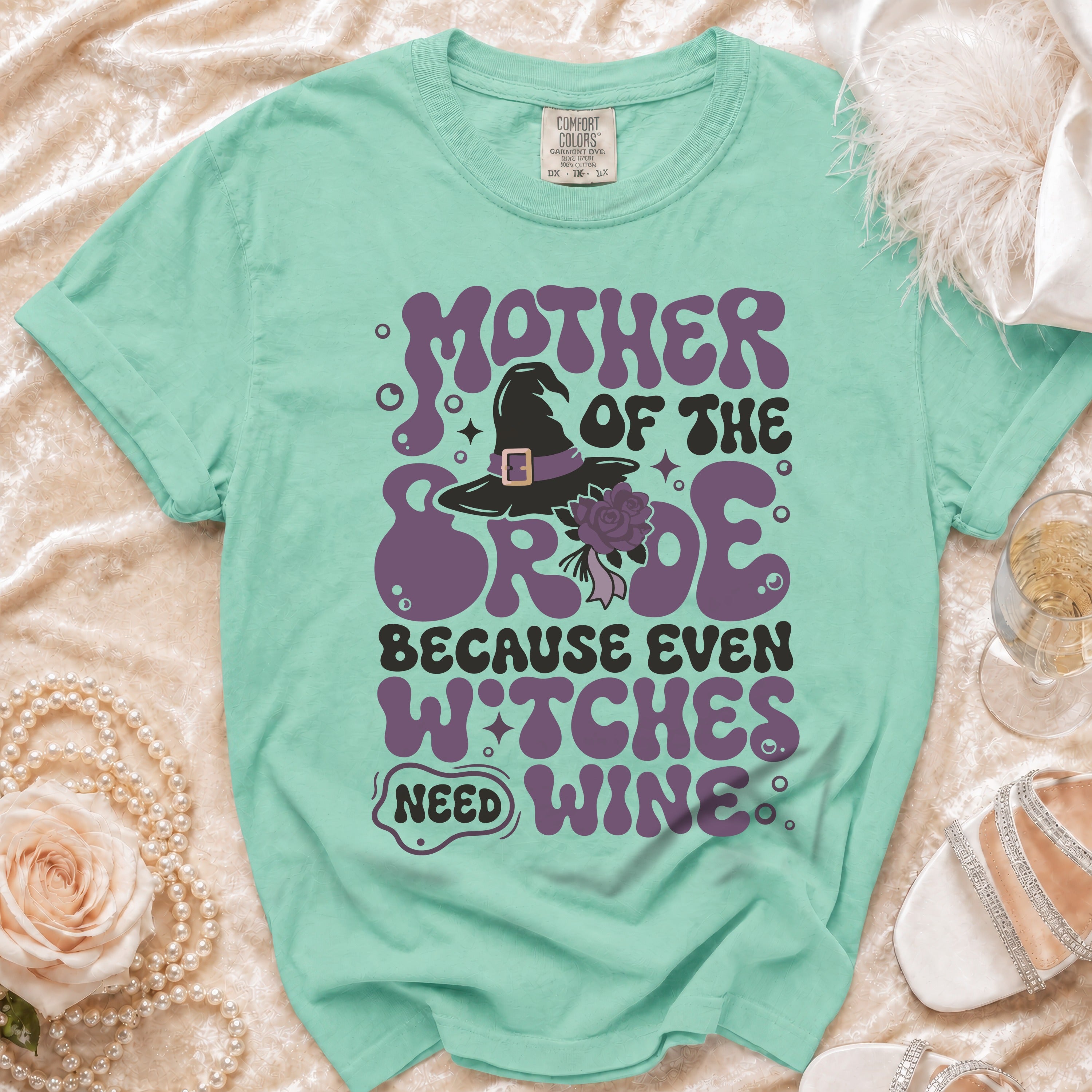 Green t-shirt with "Mother of the Bride Because Even Witches Need Wine" text and witch hat graphic.