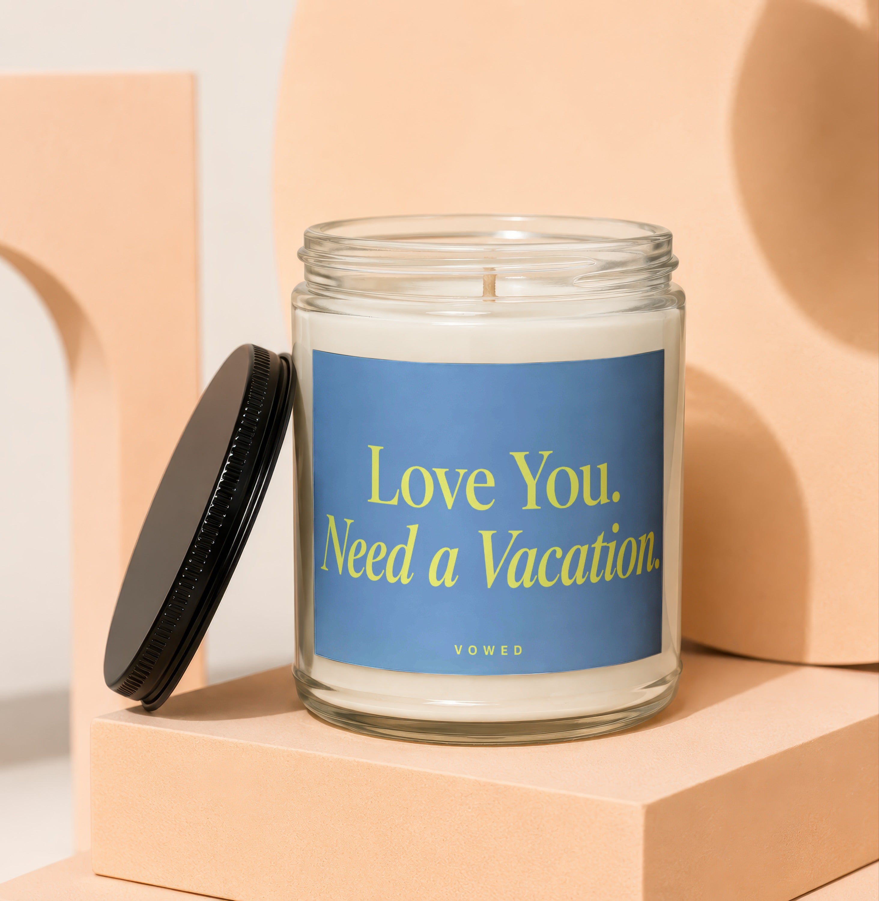 Glass candle with blue label reading "Love You. Need a Vacation."